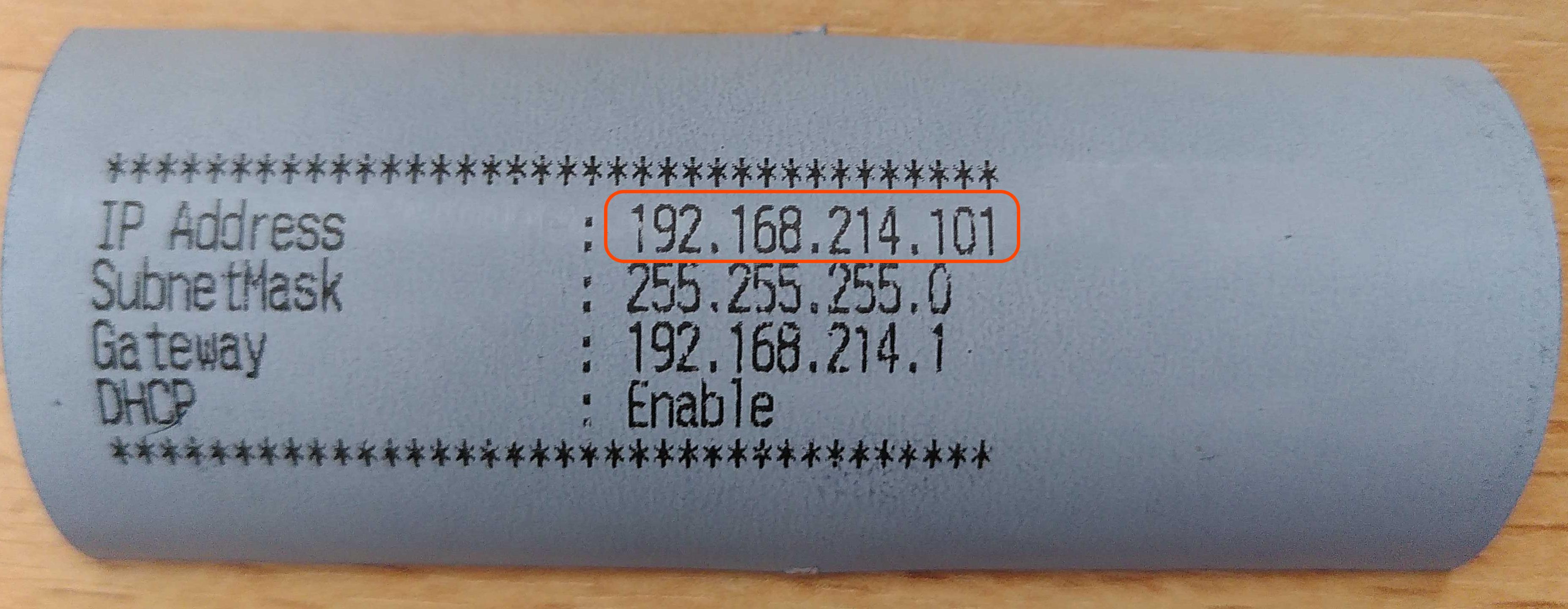 "Ein Streifen graublaues Belegpapier mit Text: IP Address 192.168.214.101 SubnetMask 255.255.255.0 Gateway 192.168.214.1 DHCP Enable"